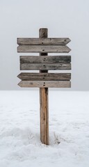 Naklejka premium Wooden directional signpost in snowy landscape