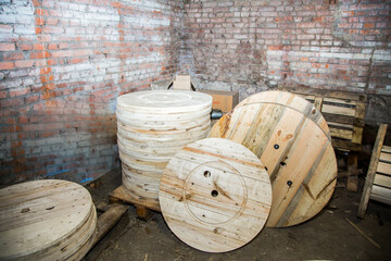 Stack of large wooden cable reels in an industrial warehouse. Cable winding and storage concept for...