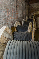 Large wooden spool with coiled cable. Warehouse of electrical wire or industrial cords for power...