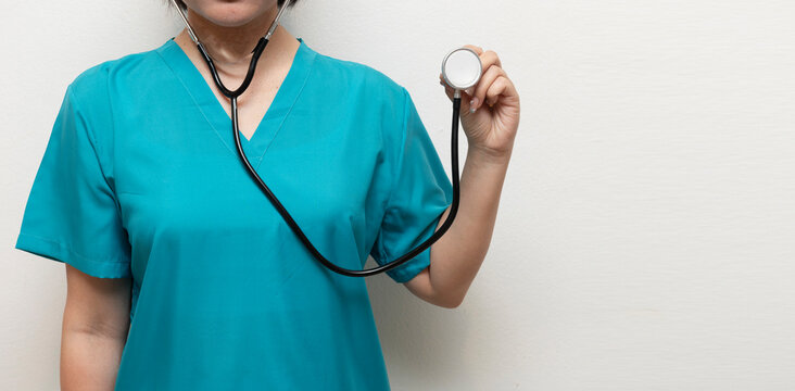 Close-up of a nurse or doctor in teal scrubs holding a stethoscope, ready for patient examination or diagnostic check