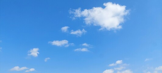 Bright white cumulus clouds floating in a clear blue summer sky. Blue sky with clouds. Soft white clouds float in the clear blue sky. Clear blue sky, bright spring, wallpaper landscape.