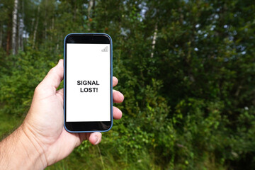 Hand holding smartphone with signal lost warning in forest
