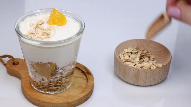 greek yogurt parfait with peaches and oats served in glass on white table