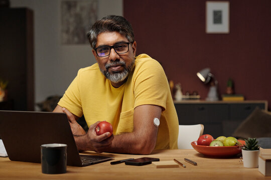 Portrait of man with insulin patch and apple at home workspace