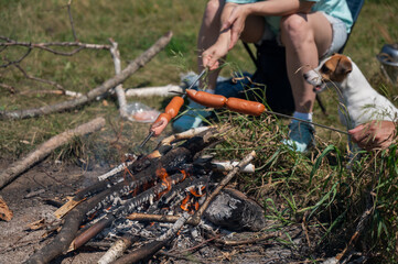Caucasian couple roasting sausages over a fire.
