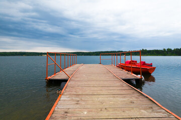 Obraz premium Pomost dla łodzi na jeziorze w lecie podczas pochmurnej pogody.
