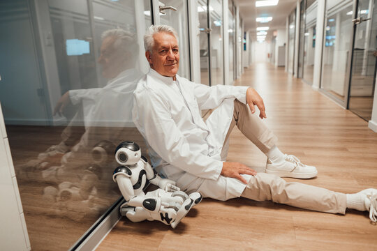 Doctor sitting with robot in medical research hallway taking a break