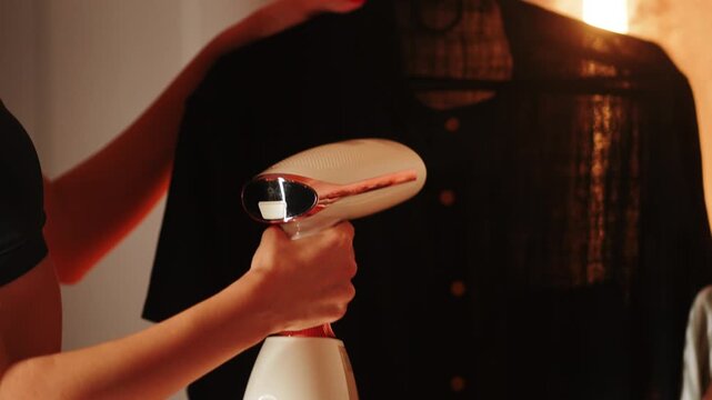 Woman expertly steaming a shirt with garment steamer in a cozy room