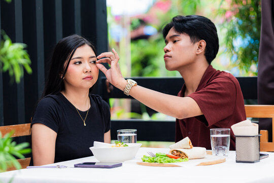 Tense couple argue and point fingers at each other in a blaming moment during lunch at an alfresco cafe.