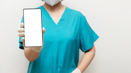 Healthcare professional in teal scrubs and gloves presents a smartphone with visible screen, representing digital tools in medical care