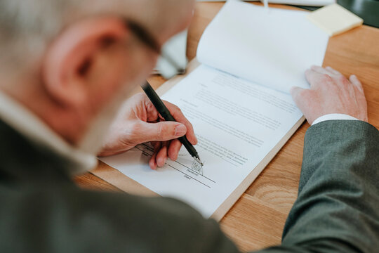 Businessperson signing agreement document in office close up