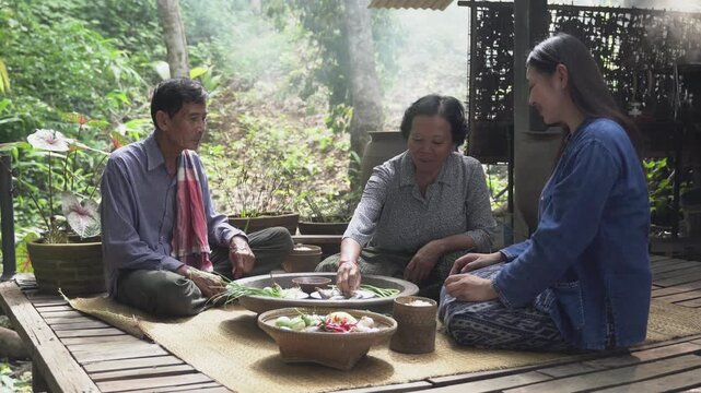 A Northeastern Thai family is happily having a meal, with the father, mother, daughter and Wathan eating together.