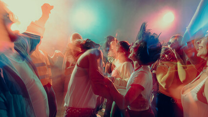 Vibrant dance party with people enjoying music, colorful lights create dynamic atmosphere, motion...