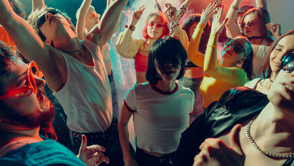 Vibrant party scene with diverse group dancing energetically under colorful lights. Concept of concert, music rhythm.