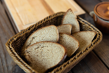 Basket filled with slices of bread. The basket is woven and sits on a wooden table. There are also...