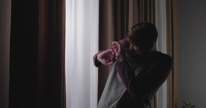 A funny European man with a beard comes to the window and sees something there. He makes a funny face of disgust.