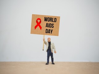 Mini toy of action figure at table with blurred background. Toy photography concept design. Minifigure of activist character with World Aids Day poster banner.