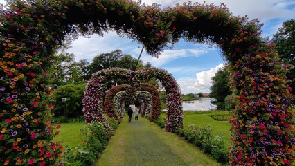 Outdoor park decorated with blooming flowers – colorful arrangements along pathways, floral arches, and pots filled with seasonal blossoms