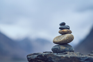 Minimalist stack of smooth stones in balance with blurred Himalayan mountain backdrop symbolizing serenity and mindfulness