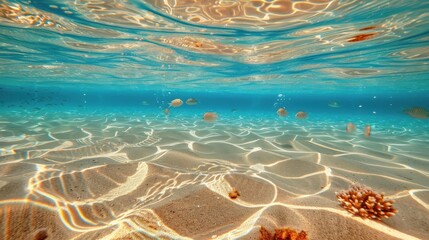 Bright underwater scene with blue water and sun rays lighting golden sand on the ocean floor