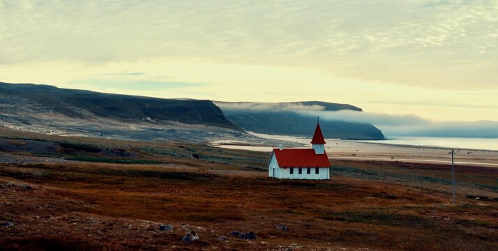 Solitary red-roofed church in Icelandic coastal landscape