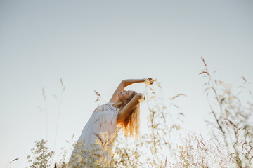 Young woman stretching in a field at sunset