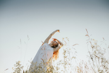 Young woman dancing in a field at sunset, embracing nature's beauty