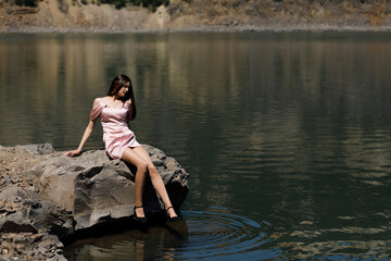 Woman in a short pink dress against the background of a lake