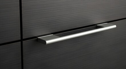 Close-up of a modern, silver drawer handle against a dark, textured cabinet.