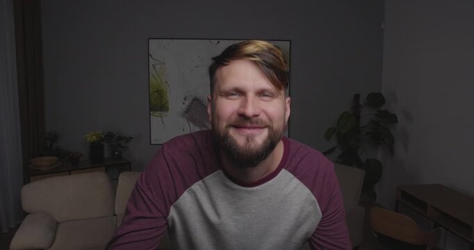 Close-up  blonde bearded European  man  looking into the camera, a mirror, or a window, smiling, moving eyebrows, flirting and dancing