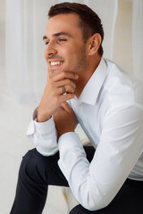 Smiling man in white shirt with striped ring, thoughtful pose