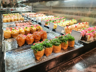 A wide variety of sushi is attractively presented in a refrigerated glass display case at a...