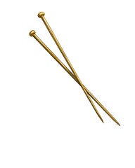 Decorative gold-colored knitting needles resting on a light surface in natural sunlight