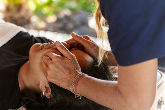 Massage therapist performing relaxing head massage outdoors - Powered by Adobe