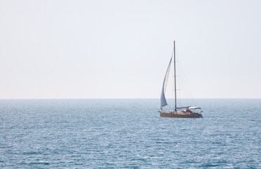 Fototapeta premium A sailboat is floating on the ocean with a clear blue sky in the background