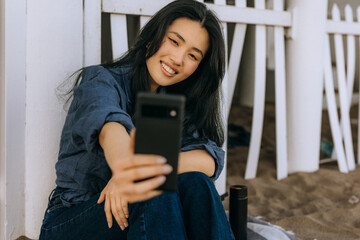 Chinese woman taking a selfie outdoors at a sandy location during daylight hours