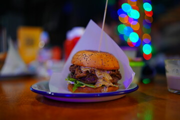  Delicious gourmet burger presented with colorful bokeh background in vibrant restaurant setting
