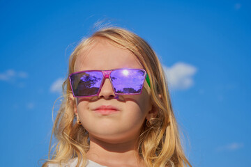 little girl in glasses on a sunny day, child looking at the sky in sunglasses purple
