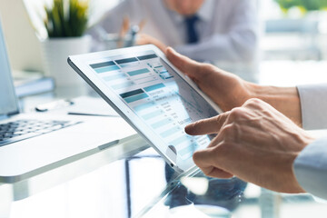 Business person analyzing financial statistics displayed on the tablet screen.
