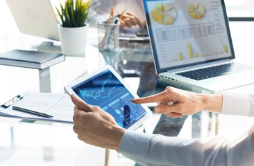 Business person analyzing financial statistics displayed on the tablet screen.