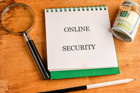 A workspace features a notepad with the phrase online security, a magnifying glass, and a bundle of banknotes, emphasizing the importance of technology in protecting finances