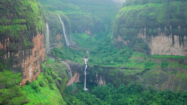 4K Slow motion shot of Devkund waterfall falling from a cliff of the Sahyadri mountain during the monsoon season as seen from Savlya Ghat view point in Raigad district, Maharashtra, India. Scenic view