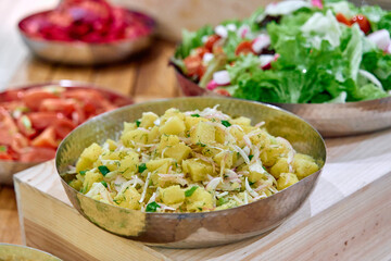 A Vibrant Serving of Potato Salad with Fresh Vegetables and Herbs, Complemented by Colorful Sides in a Rustic Setting