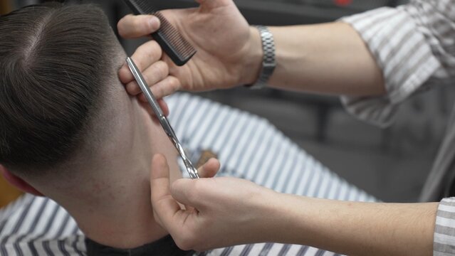 Professional barber cutting client's hair with scissors and comb, creating a stylish fade in a modern barbershop, providing a high quality grooming service