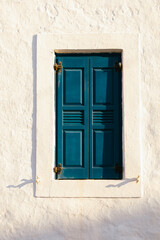 Dark teal wooden shutters on a traditional white wall