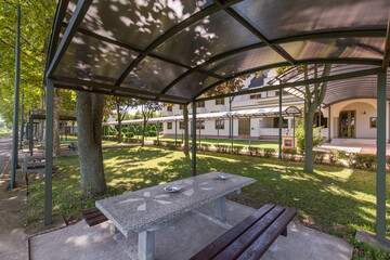 Outdoor area with covered seating, stone picnic tables, wooden benches