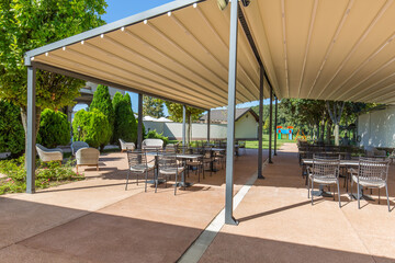 Outdoor dining terrace with several empty tables on a sunny day.