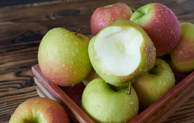 Bitten apple. Seasonal apples in a wooden box.