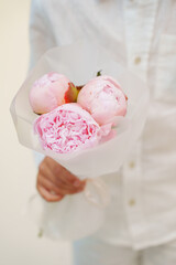 Beautiful pink peony bouquet presented by a person in casual attire