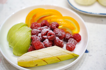 Fresh fruit platter with raspberries, apples, and oranges at breakfast